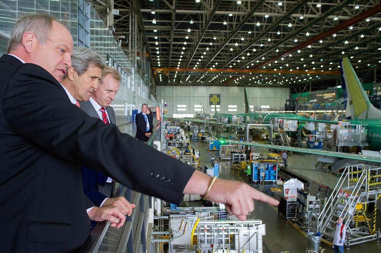 The Boeing 737 assembly line at the Renton, Washington plant, with a partially built fuselage on the line and factory staff walking beside it.
