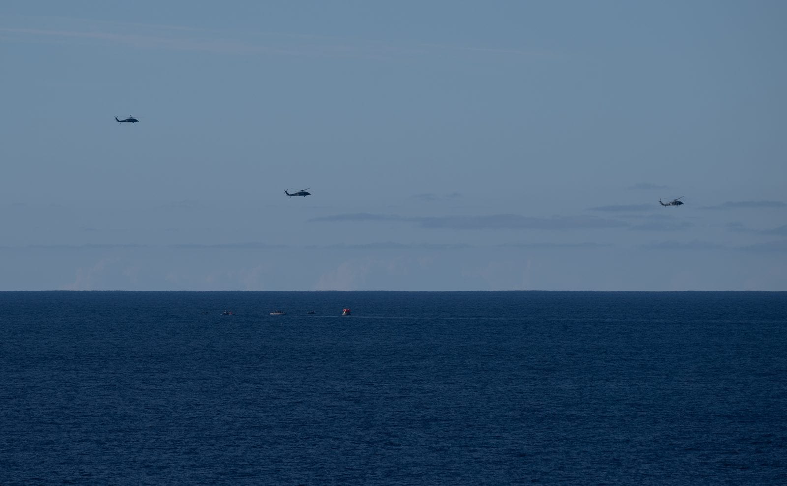 U.S. Navy MH-60 Seahawk helicopters and recovery boats approaching the Orion capsule on the Pacific Ocean after splashdown, April 10, 2026.