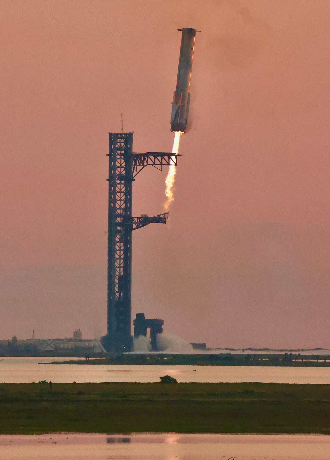 Super Heavy booster on final approach back to the launch tower during Flight 5, engines still lit.