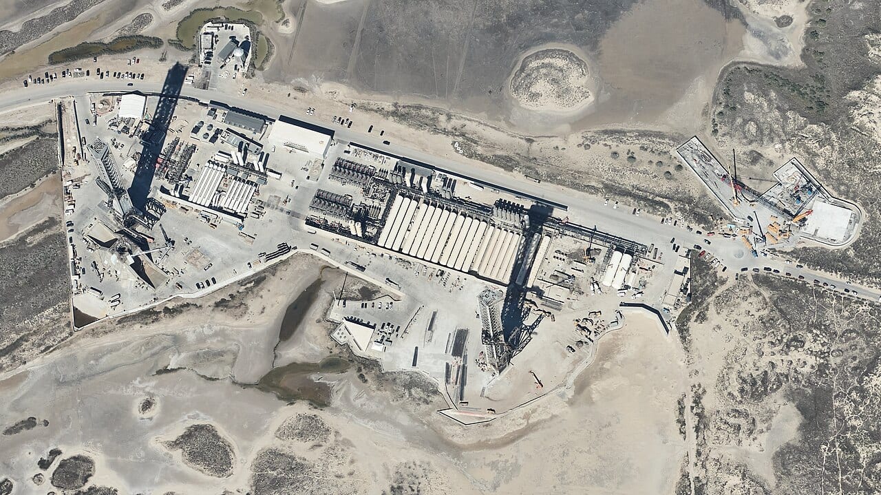 Aerial view of the SpaceX Starbase launch site in Texas, showing the launch and catch tower alongside the rest of the pad infrastructure.